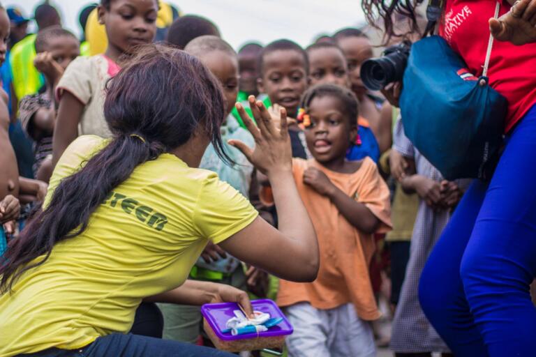 A community leader greeting children with a high-five